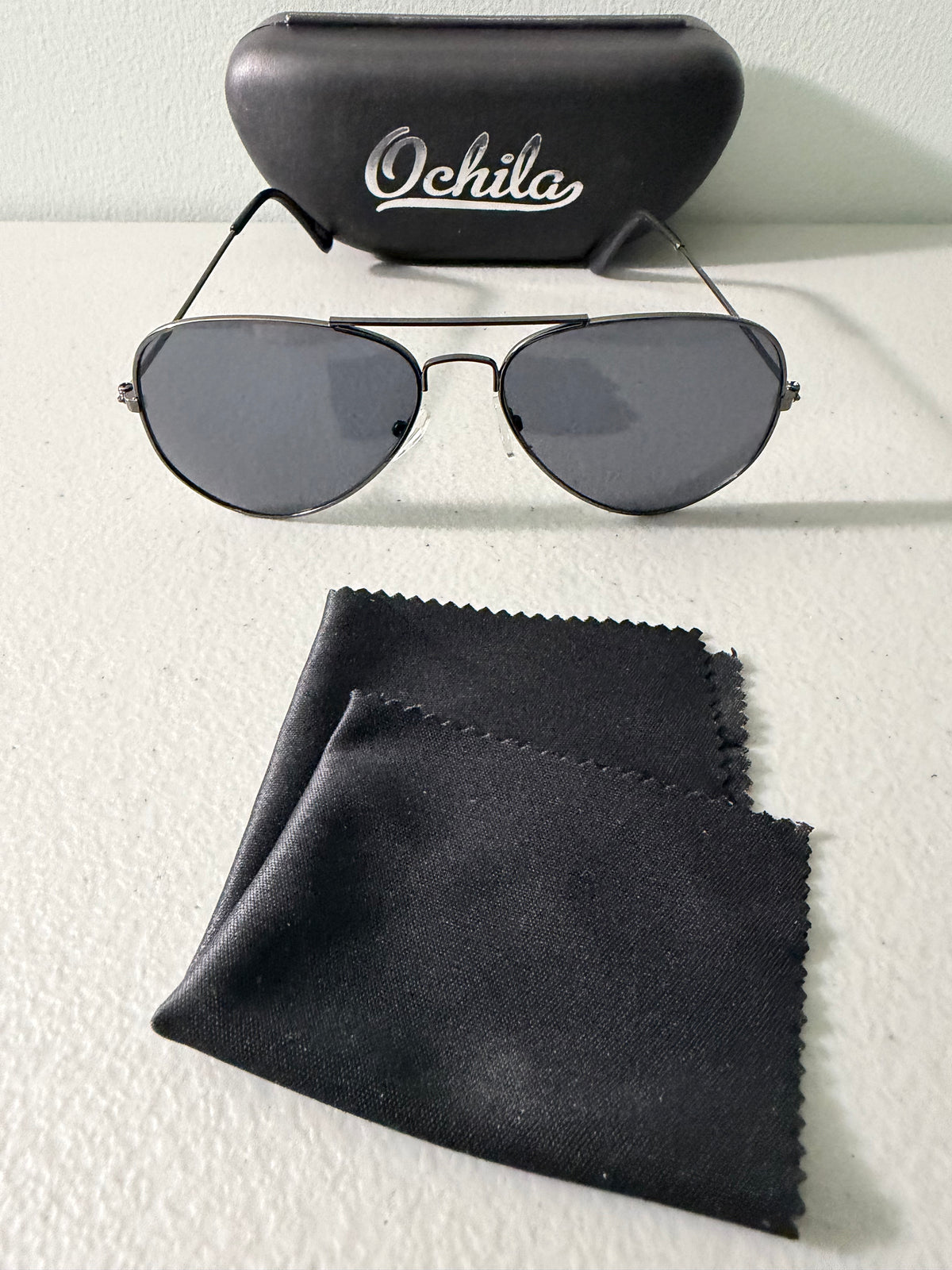 Brand new Ochila pilot aviator sunglasses. Silver frame with smoke gray lenses. comes with hardshell case an a microfiber cleaning cloth