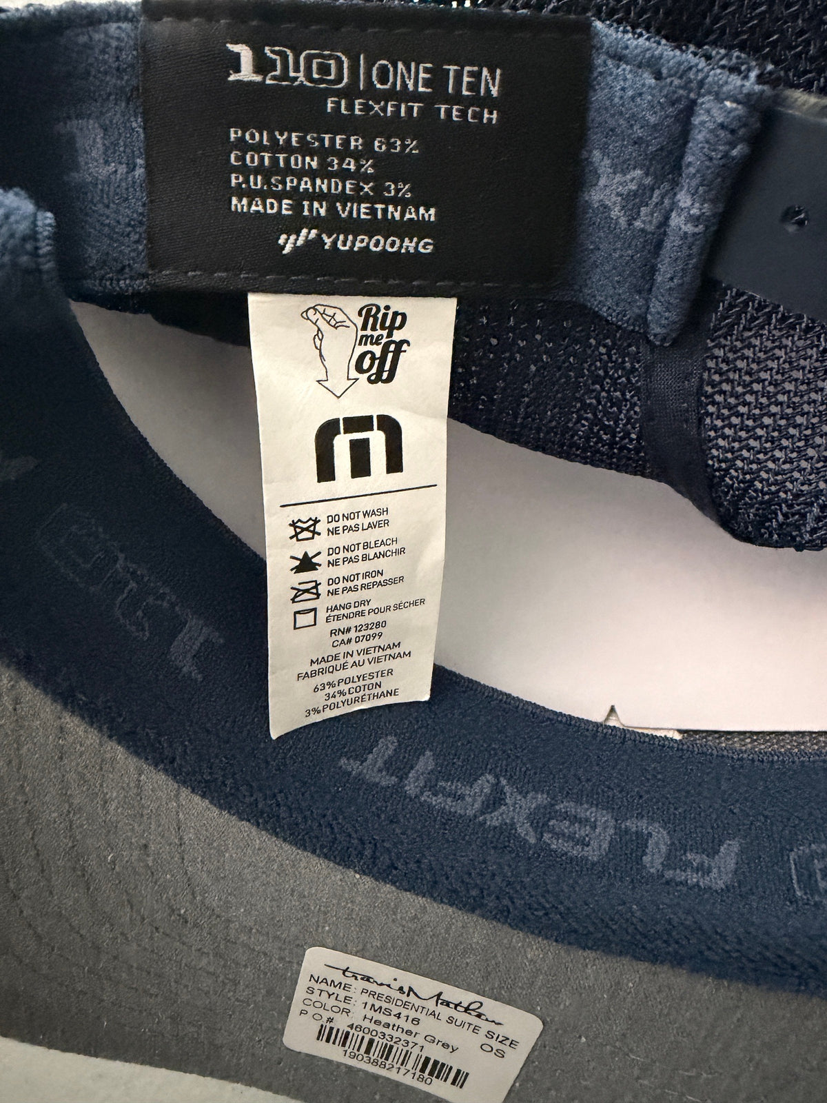 Brand Tag: Brand new Travis Mathew Bush Wood CC 1980 Caddy Day Golf Tournament Champion trucker hat featuring a heather gray structured crown, an embroidered champion patch, dark blue mesh backing, and a gold FlexFit 110 sticker from Bell's Bargain Barn.