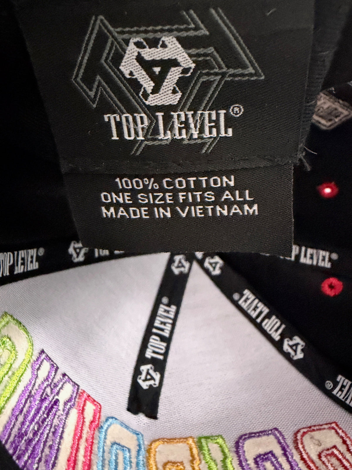Inside view of the Top Level DRIPPING hat showing the authentic brand tag, and 100% cotton fabric material label.