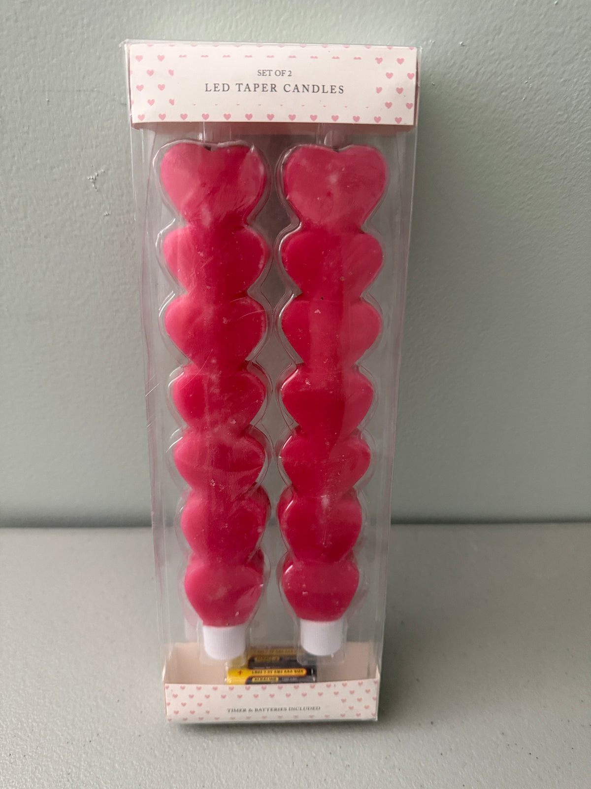 Factory-sealed 2-pack box of At Home Red Heart LED Taper  Candles, showcasing two stacked heart-shaped flameless sticks with included batteries.