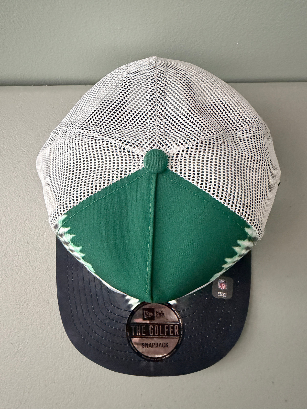 Top View: Front profile shot of a brand new New Era New York Jets The Golfer snapback hat featuring a green and white sublimated tie dye front panel, premium embroidered white jets logo, gray structured brim, and breathable white mesh trucker backing. 