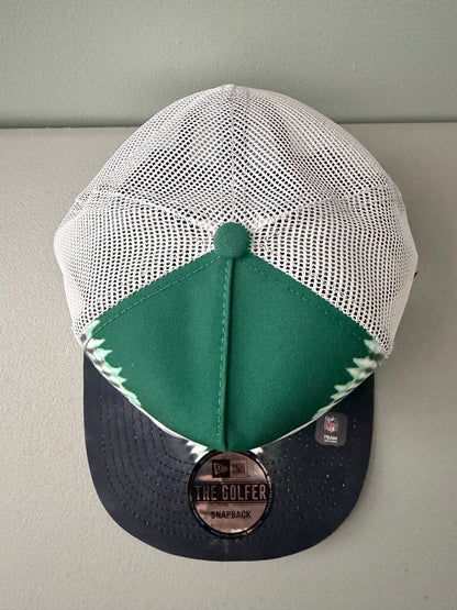 Top View: Front profile shot of a brand new New Era New York Jets The Golfer snapback hat featuring a green and white sublimated tie dye front panel, premium embroidered white jets logo, gray structured brim, and breathable white mesh trucker backing. 