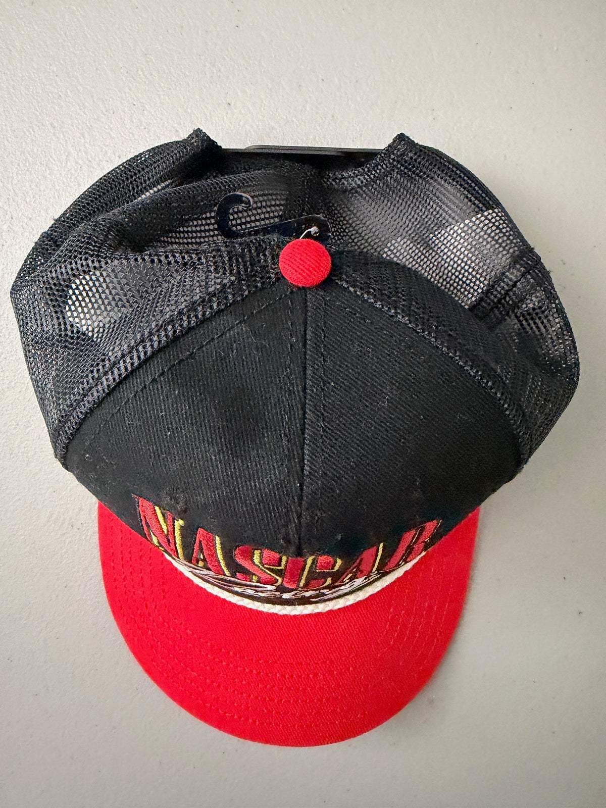 Top View: Brand new 2026 NASCAR racing rope trucker hat in black and red, featuring a vibrant embroidered front logo, white braided rope trim, and adjustable snapback closure