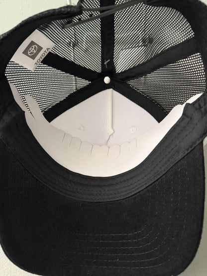 Inside View: Brand new Toyota Off-Road Racing rope trucker hat in black and white, featuring a large embroidered retro shield logo patch, checkerboard racing stripes, and a braided white rope detail on a snapback cap from Bell's Bargain Barn.
