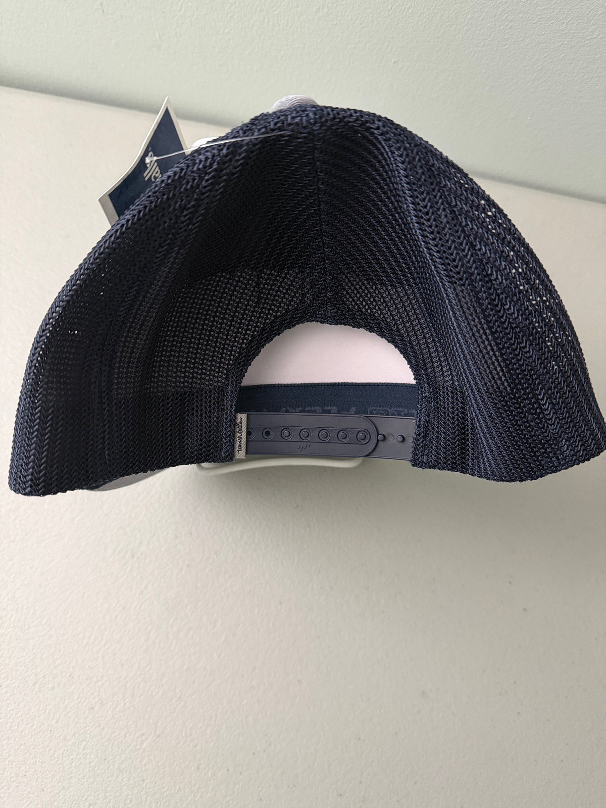 Back View: Brand new Travis Mathew Bush Wood CC 1980 Caddy Day Golf Tournament Champion trucker hat featuring a heather gray structured crown, an embroidered champion patch, dark blue mesh backing, and a gold FlexFit 110 sticker from Bell's Bargain Barn.
