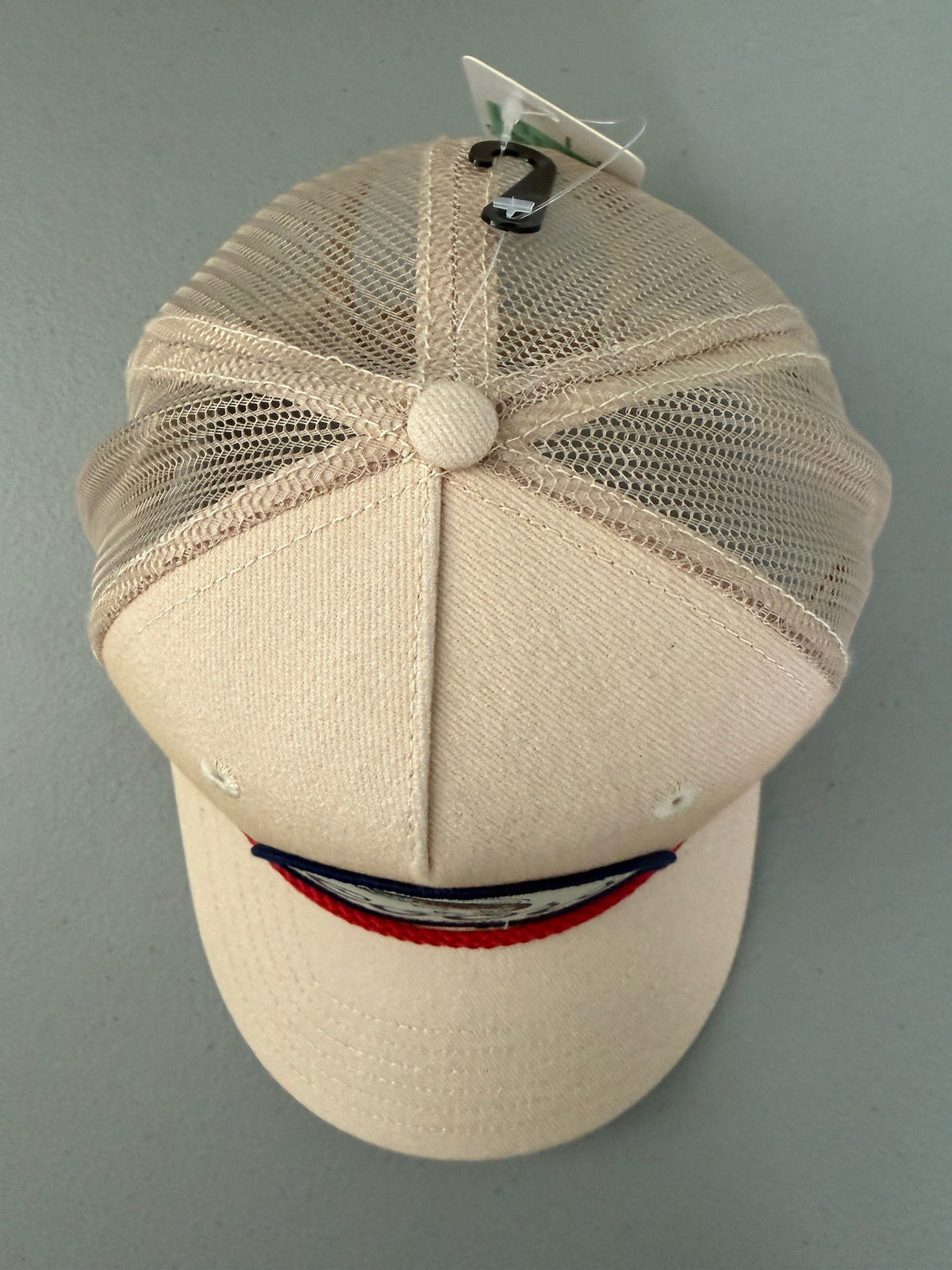 Top View: Brand new Coors Banquet Beer Fy Fishing mesh trucker hat featuring a cream structured crown, an embroidered oval patch with a rainbow trout graphic, tan mesh panels, a bright red braided front visor rope, and a snapback closure from Bell's Bargain Barn