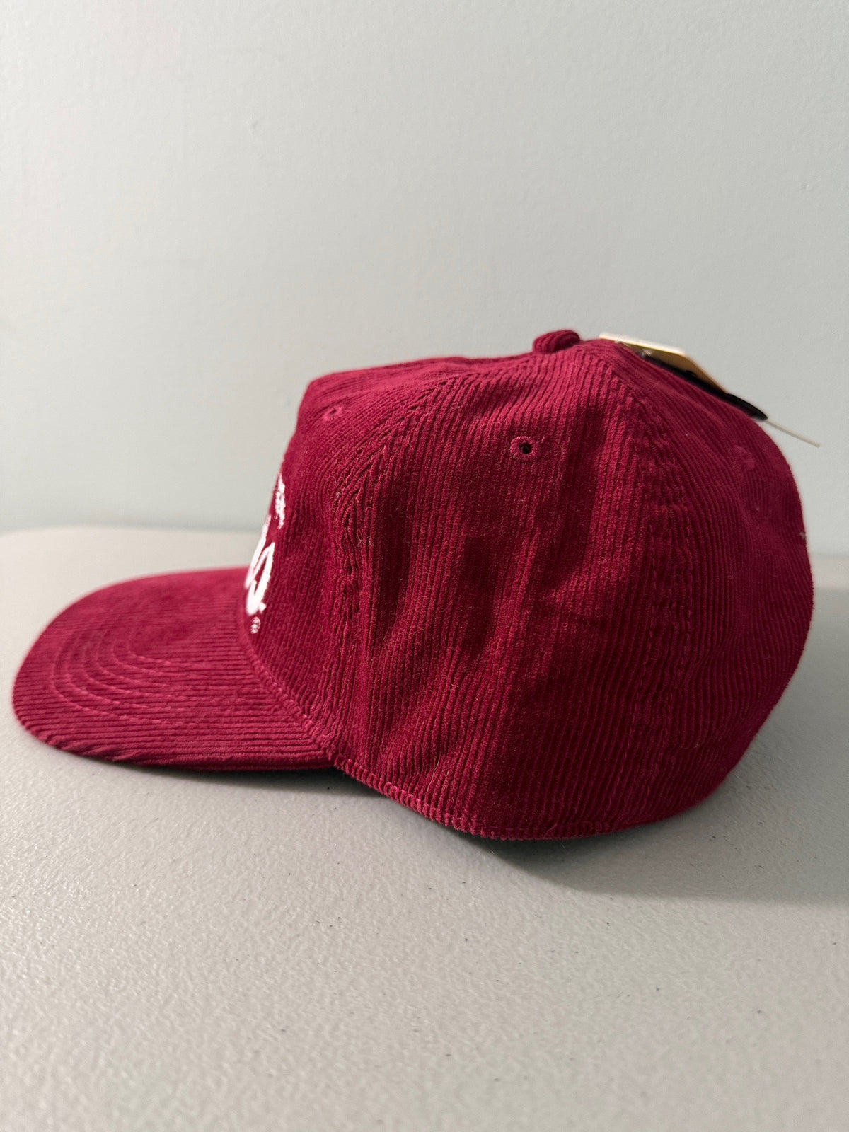 Side View: Brand new Coors Banquet Beer corduroy baseball hat featuring a deep maroon structured corduroy crown and brim, white embroidered classic script logo on the front panel, and an adjustable snapback closure from Bell's Bargain Barn.