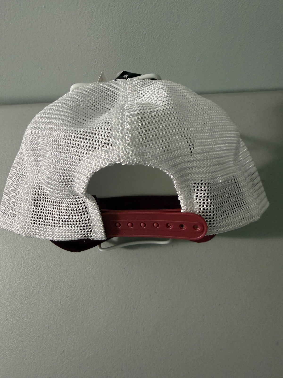 Back Closure View: Brand new Southern Comfort Take It Easy mesh trucker hat featuring a structured maroon front foam panel, raised gold cursive lettering, white mesh back panels, a patterned front visor accent rope, and an adjustable snapback closre from Bell's Bargain Barn. 