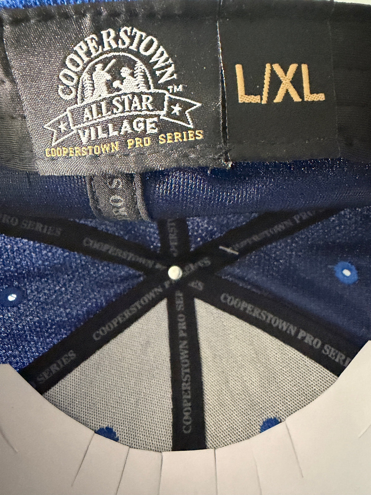 Branded Tag /Size View: Brand new royal blue Cooperstown All Star Pro Village Pro Series stretch fit baseball hat featuring an embroidered red and white tournament patch, a diamond-shaped L/XL silver visor sticker, and an athletic mesh-textured crown from Bell's Bargain Barn. 