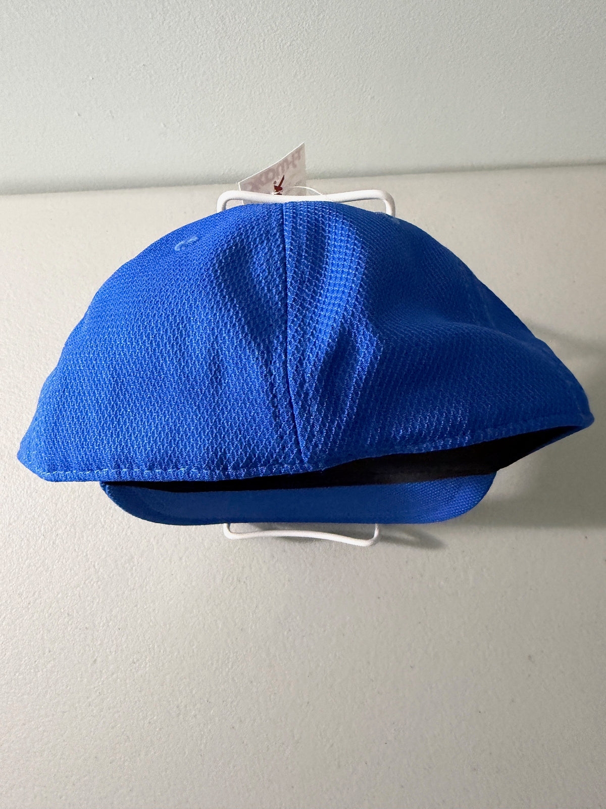 Back View: Brand new royal blue Cooperstown All Star Pro Village Pro Series stretch fit baseball hat featuring an embroidered red and white tournament patch, a diamond-shaped L/XL silver visor sticker, and an athletic mesh-textured crown from Bell's Bargain Barn. 