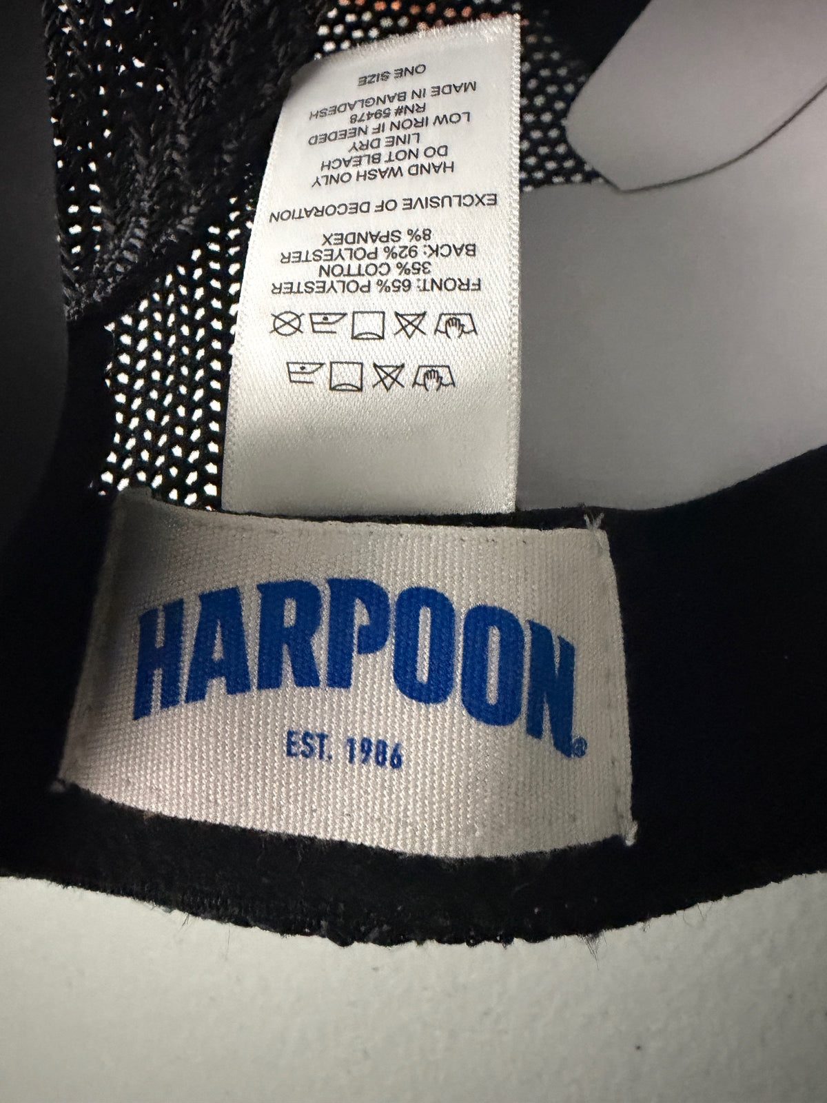 Product Tag View: Brand new Harpoon Brewery Est. 198 mid crown fit trucker hat featuring a structured off-white front panel with a black embroidered logo patch, black mesh backing, a thin black visor rope, and a blue brim sticker from bell's Bargain Barn.