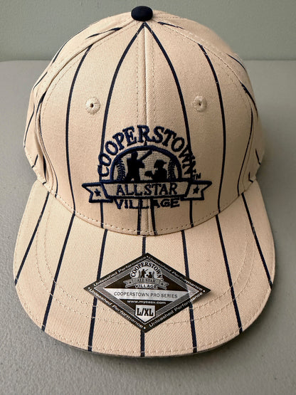 Brand new cream Cooperstown All Star Village Pro Series stretch fit baseball hat with navy blue pinstripes, featuring an embroidered navy tournament logo patch and a silver diamond-shaped L/XL visor sticker from Bell's Bargain Barn.  