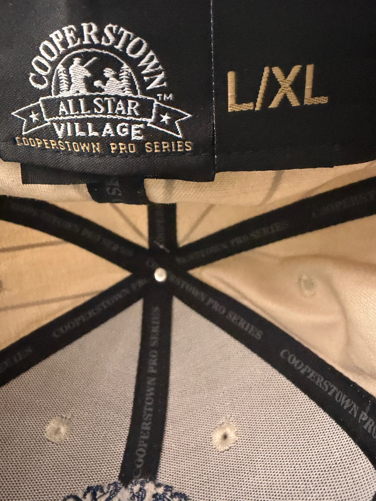 Brand & Size Tag: Brand new cream Cooperstown All Star Village Pro Series stretch fit baseball hat with navy blue pinstripes, featuring an embroidered navy tournament logo patch and a silver diamond-shaped L/XL visor sticker from Bell's Bargain Barn.  