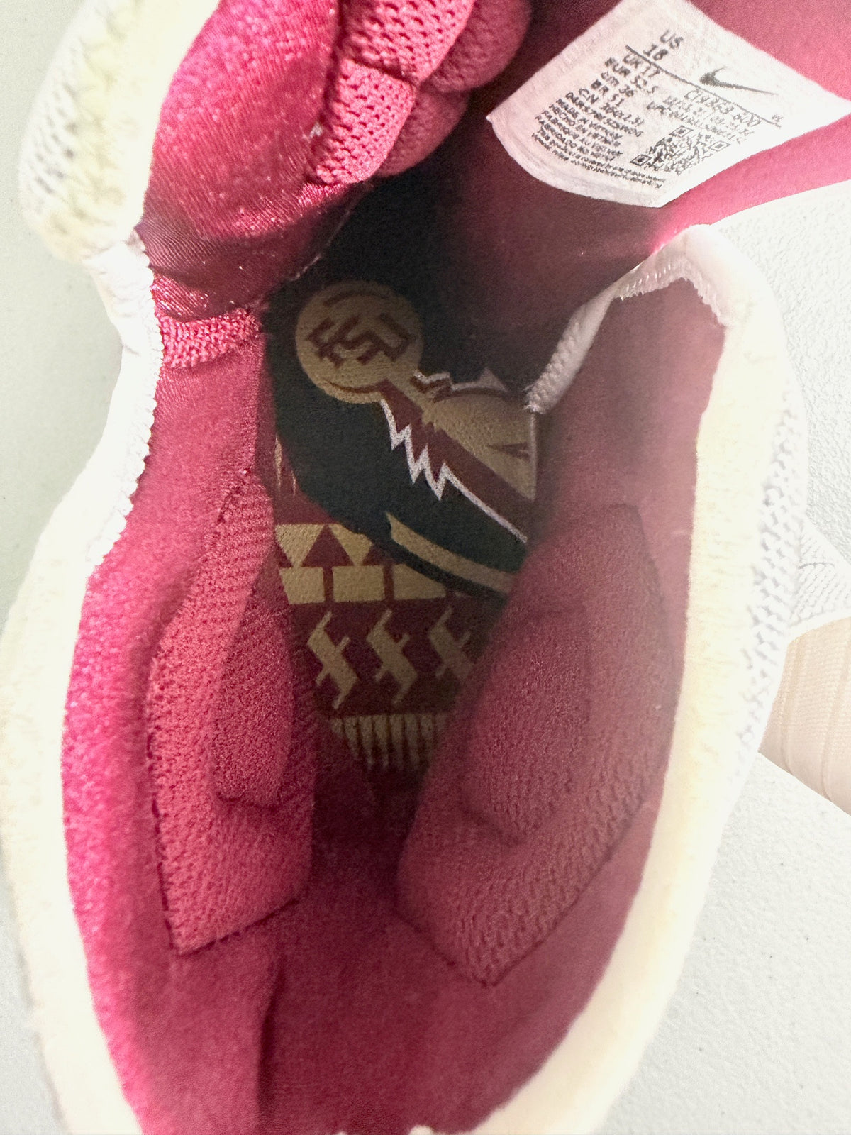 Close-up of the interior of a Nike Force Savage Elite 2 Player Exclusive (SMUFSU showing a gold and maroon knit lining, a white mesh collar, a patterned insole with gold, burgundy, and black geometric details, and a white tag with printed text. Rare Size 18 (Big & Tall). Bell's Bargain Barn.