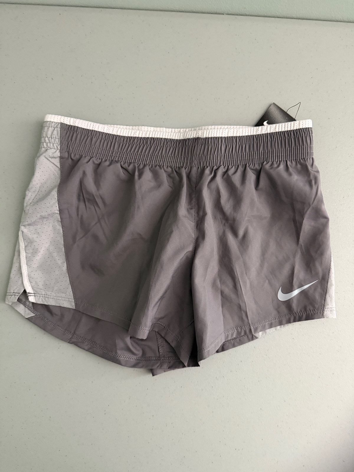 Front view of brand new Nike Women's 10K running shorts in grey with white mesh side panels and white Swoosh logo.