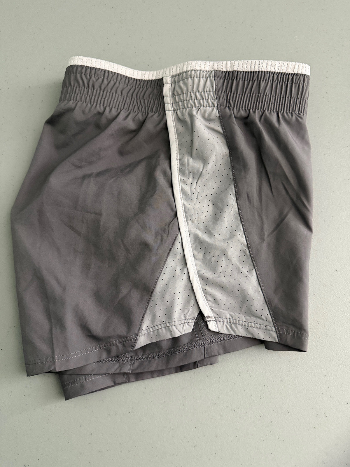 Side view of Nike Women's 10K athletic shorts in grey, showing the  reflective accents. 