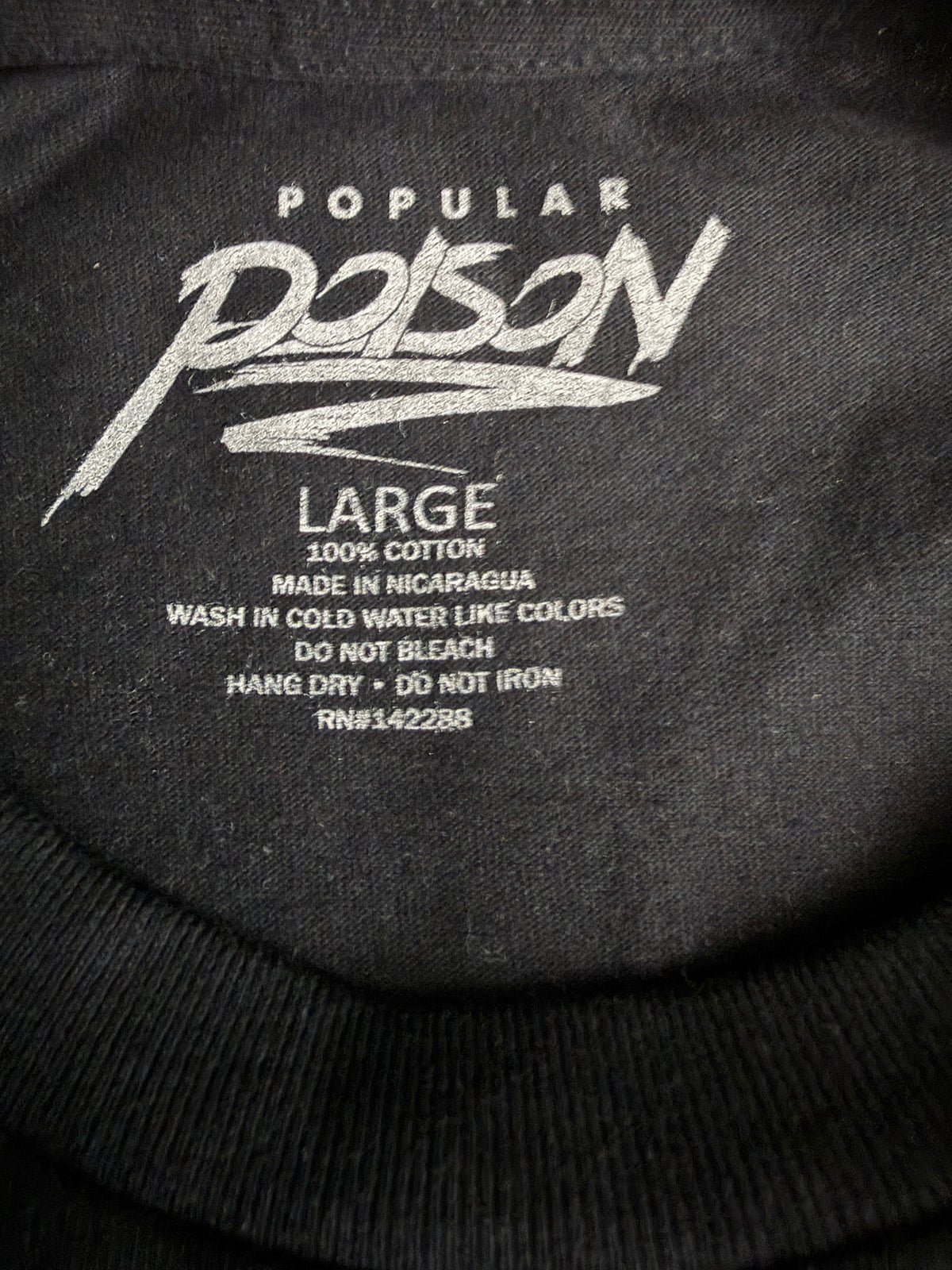 Close-up detail of the brand graphic size tag on the Popular Poison "The World Is Yours" angel graphic t-shirt in black and white 