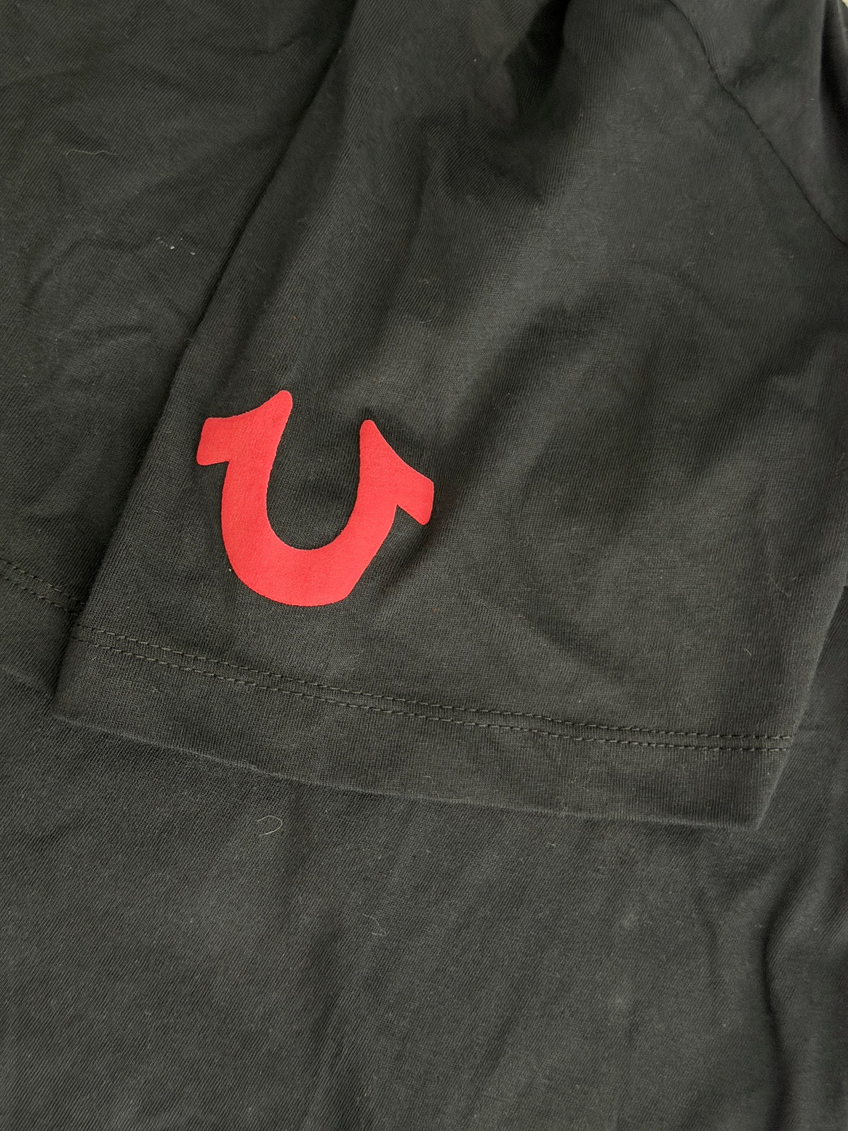 Close-up of a brand new black True Religion size Large T-shirt showing a red  horseshoe graphic on the left sleeve. 