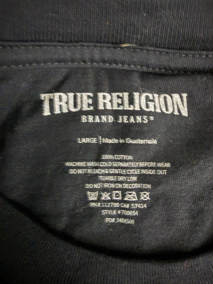 Close-up of the inside neck label of a NWT black True Religion Graphic T-shirt reading True Religion brand jeans, with size and care instructions printed in white text.
