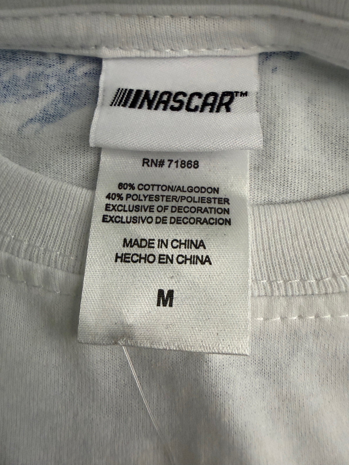 Size Tag Detail: Close-up of the inner neck collar showing the official NASCAR branding, size Medium and product care tag on the white graphic tee shirt. 