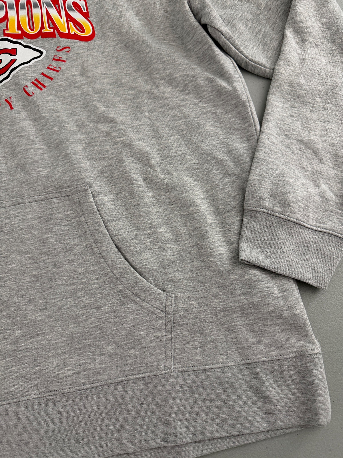 Close-up View of kangaroo pockets on a Brand new gray Men's Kansas City Chiefs Super Bowl LVIII Champions pullover hoodie sweatshirt.