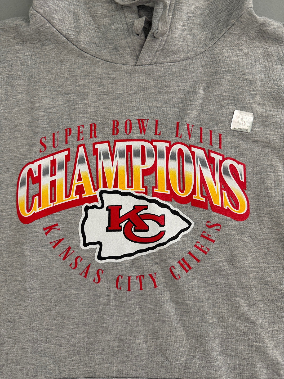 Detailed view of the vibrant Kansas City Chiefs Super Bowl LVIII Champions official team graphic printed on the chest of a gray hoodie. 