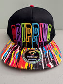 Front view of a black Top Level DRIPPING Snapback hat showcasing the bold, 3D raised rainbow-colored embroidered text and the multicolor paint splatter flat bill on a neutral bakground.